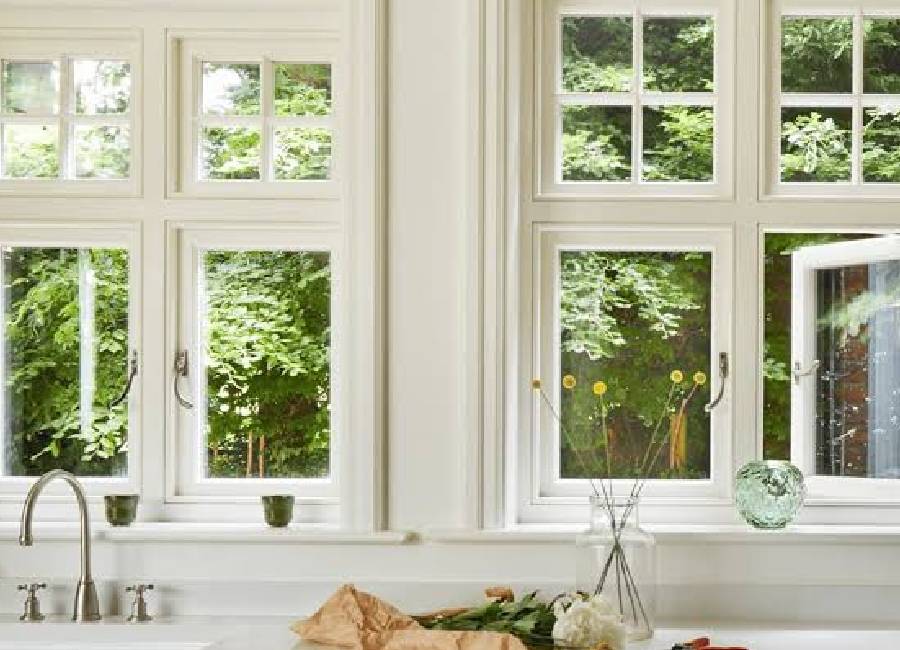 Black-framed energy efficient windows with a linen-draped oak window seat overlooking a garden